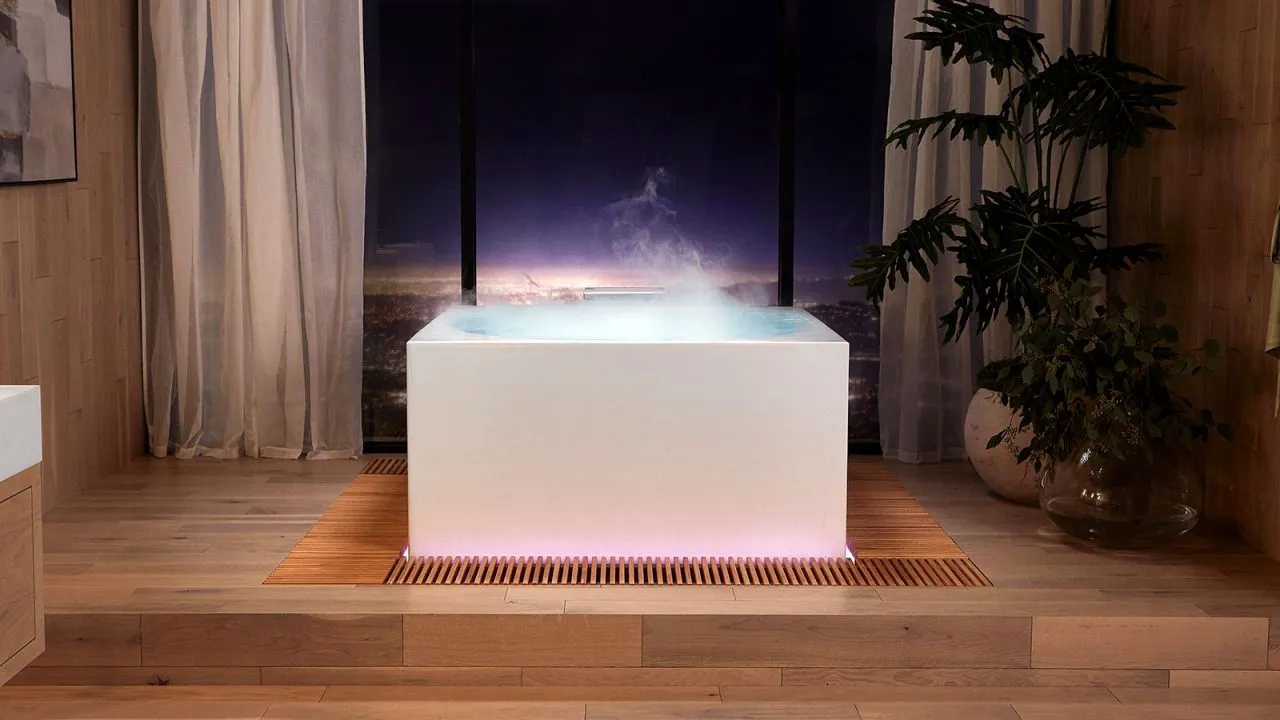 Freestanding Kohler Stillness bathtub with soft steam in a timber-lined wellness space